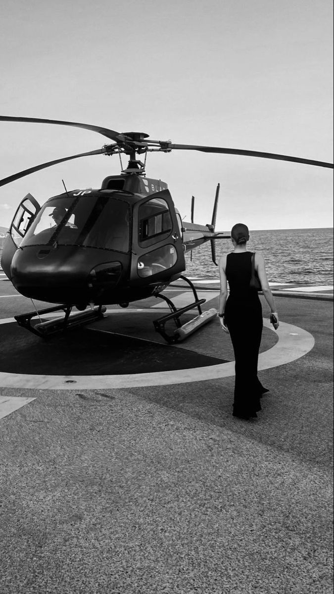 Elegant woman approaching luxury helicopter on yacht helipad