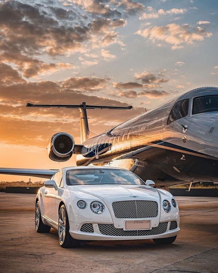 Luxury Bentley and private jet on tarmac at golden hour sunset
